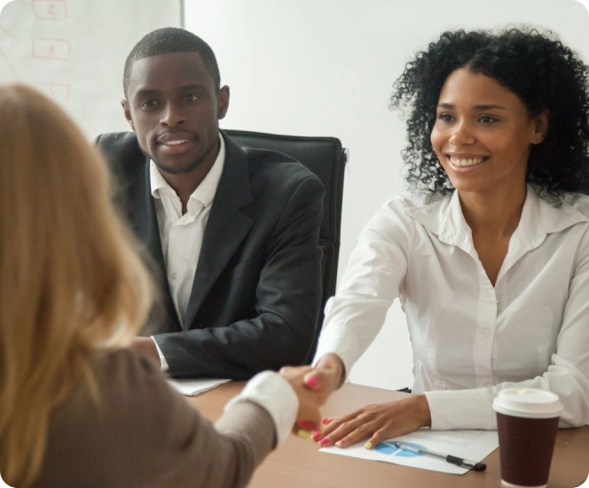 A woman shaking hands with another person at a table.