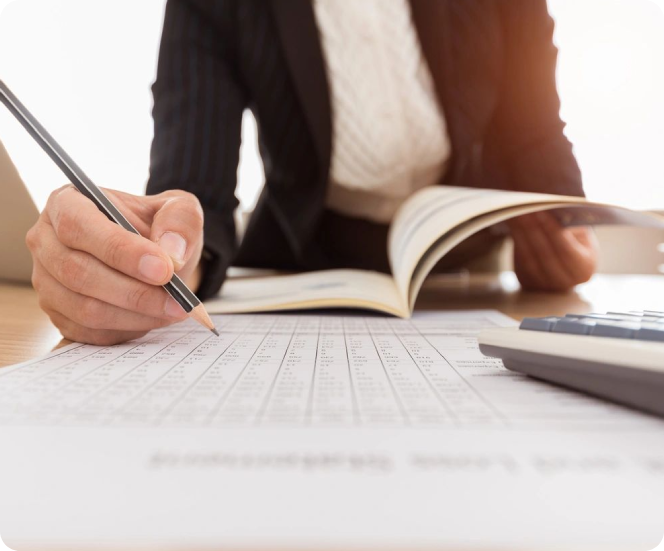 A person writing on a book while sitting at a desk.