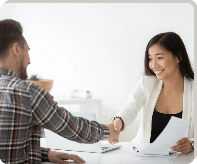 A man and woman shaking hands over papers.